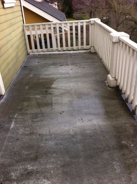 Concrete deck landing and stairway before pressure washing, streaked with grime