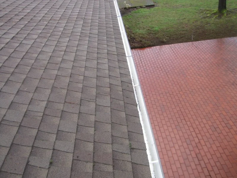 Clean gutter line along a roof edge next to a brick paver patio